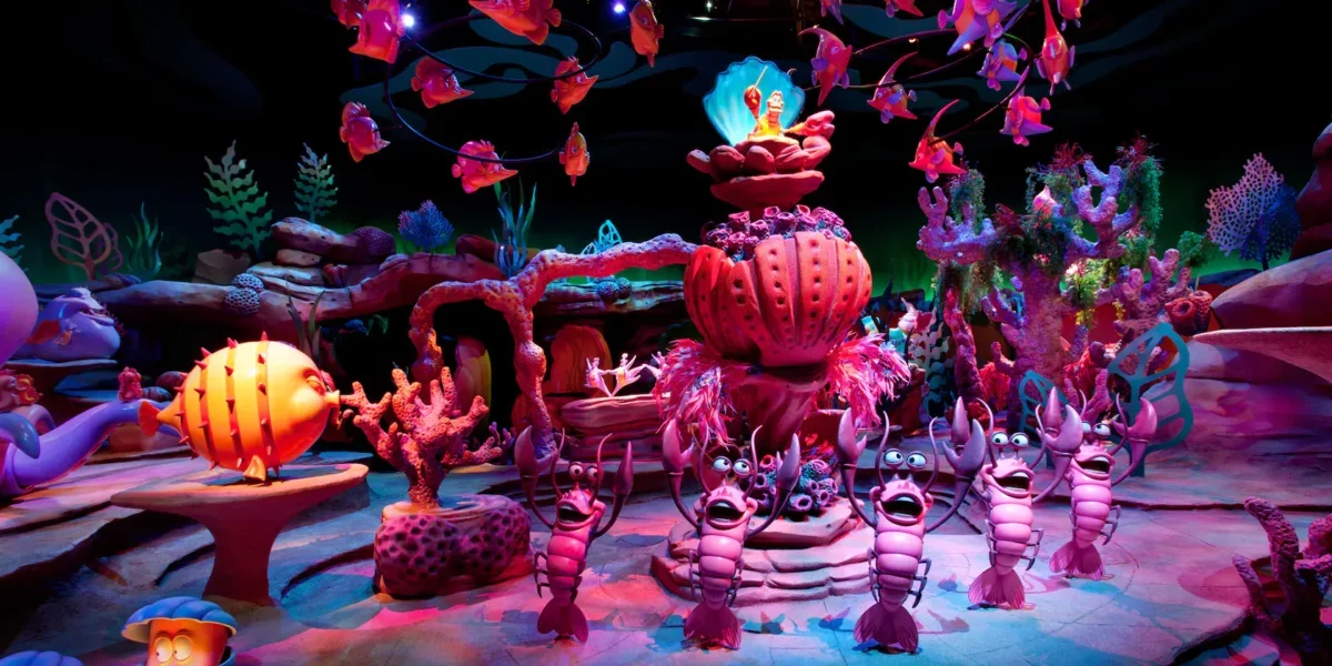 Vibrant undersea world with lively sea creatures and glowing coral, channeling The Little Mermaid ride’s magical Disney energy.