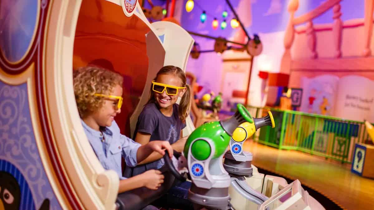 Children in 3D glasses shoot targets in a Toy Story Midway Mania vehicle