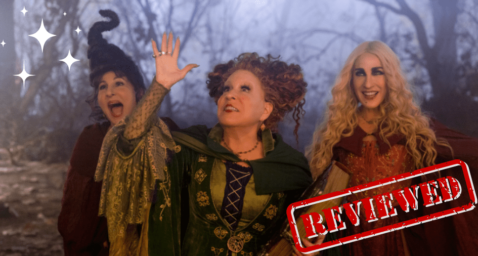 The Sanderson Sisters from Hocus Pocus 2 come to life in their signature witch costumes, gathering in a spooky forest scene reminiscent of a Halloween Horror Nights maze, with "REVIEWED" boldly stamped in red across the image.