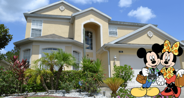 Mickey and Minnie Mouse greet guests in front of a picturesque Disney World villa, its cheerful yellow facade standing out amid lush gardens beneath the bright blue Orlando sky.