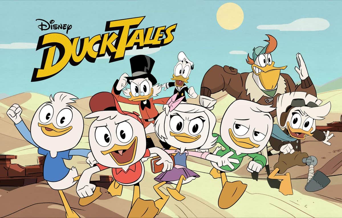 The DuckTales gang dashes through a sun-soaked desert, with the iconic DuckTales and EPCOT DuckTales Adventure logos overhead, set against a backdrop of rolling hills and blue sky—capturing the excitement of a Disney Parks adventure.