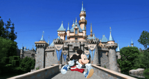 Mickey Mouse dashes in front of Disneyland’s enchanting fairytale castle, its blue spires shining under a vibrant sky, bringing the runDisney adventure to life with the irresistible magic and energy fans love about Disney parks.