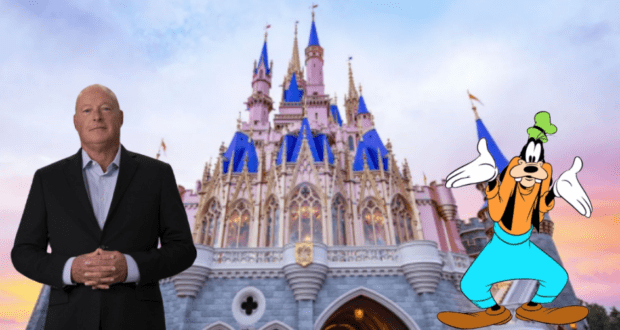 A guest and Goofy pose together in front of Cinderella Castle with its iconic blue spires glowing at sunset, capturing the enchanting atmosphere that defined Disney Parks during Bob Chapek's era.
