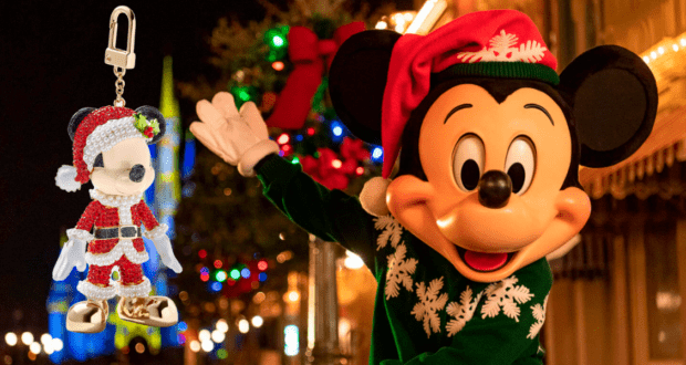 Mickey Mouse sporting a Santa hat waves cheerfully at Disney World, with a Mickey-shaped Santa ornament and festive BaubleBar Disney jewelry sparkling in the foreground.