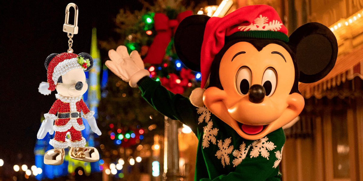 Mickey Mouse sporting a Santa hat waves cheerfully at Disney World, with a Mickey-shaped Santa ornament and festive BaubleBar Disney jewelry sparkling in the foreground.