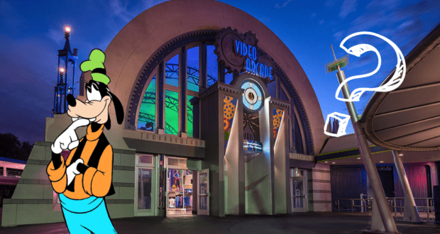 Goofy pauses in front of the glowing Tomorrowland Light & Power Co arcade entrance at Magic Kingdom after dark, striking a thoughtful pose with a big question mark beside him.
