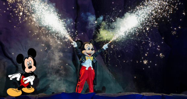 Mickey Mouse dazzles in a classic tuxedo, holding sparklers and radiating showtime excitement, while an animated Mickey waves nearby—celebrating the enchanting spirit of Hollywood Studios’ Fantasmic!.