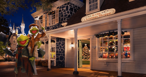 Kermit and another Muppet, dressed in Victorian attire, pose outside a beautifully decorated Christmas shop on a winter night at the Disney Parks, capturing that enchanting holiday magic that makes for an unforgettable Disney PhotoPass memory.