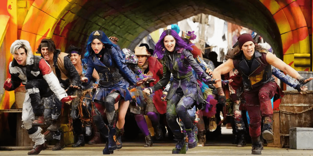 Teens in vibrant, punk-inspired outfits dash with excitement beneath a dramatic archway, eager to dive into the adventure and thrills of Disney Villains Land.