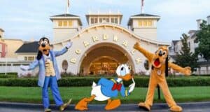 Goofy, Pluto, and Donald Duck smile for a photo in front of Disney’s Boardwalk Resort entrance, ready to kick off an exciting day of exclusive Disney Resort experiences.