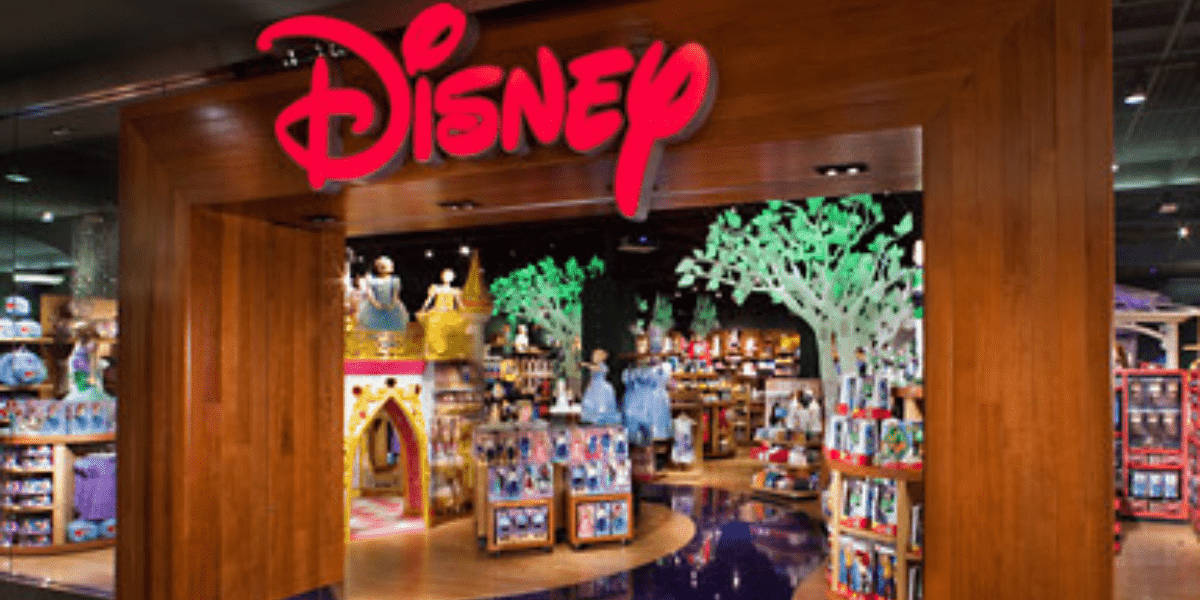 The entrance to a Disney Store featuring the iconic red Disney logo, with shelves stocked full of beloved character toys and magical merchandise inviting fans inside.
