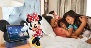A family snuggles together in bed, surrounded by Disney magic with a Minnie Mouse-themed smart display and Minnie Mouse illustration close by, as the Hey Disney voice assistant creates an enchanting bedtime experience worthy of a night at a Disney Resort.