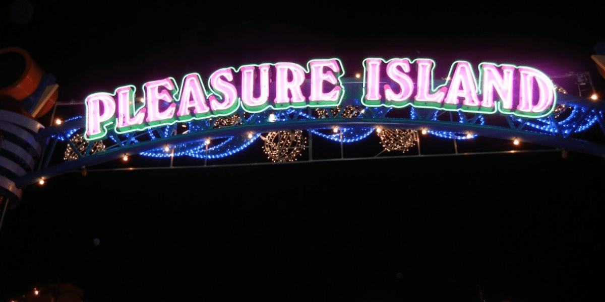 The iconic "Pleasure Island" neon sign shines vividly against the night sky, with strings of glowing lights below, capturing the electric energy and party atmosphere that made Disney Springs’ nightlife legendary among theme park fans.