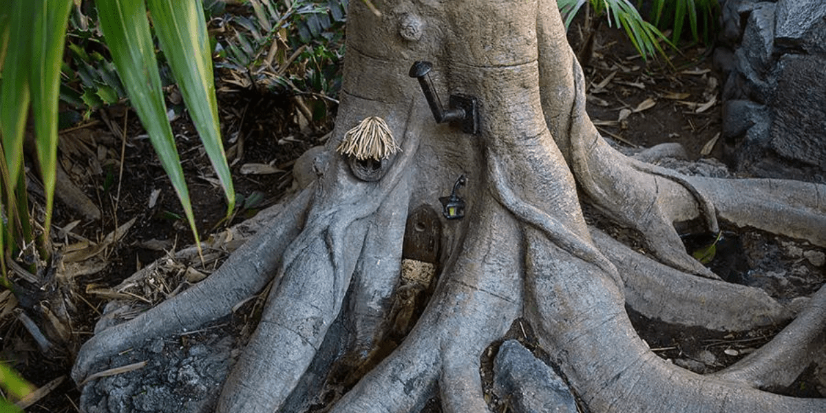 Enchanted tree roots form a whimsical fairy cottage with a tiny door, broom, glowing lantern, and straw roof—just like the magical storybook houses you’d discover in Disney Parks attractions or Little Golden Books adventures.