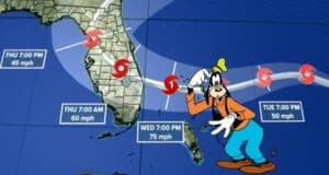 Goofy stands in front of a hurricane track map displaying Storm Nicole's projected paths across Florida, drawing attention to how the approaching storm could affect Walt Disney World.