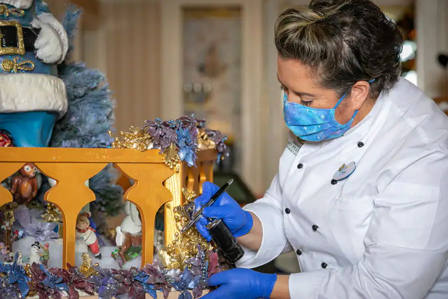 a pastry chef works on Disney's grand floridian's life-size gingerbread house