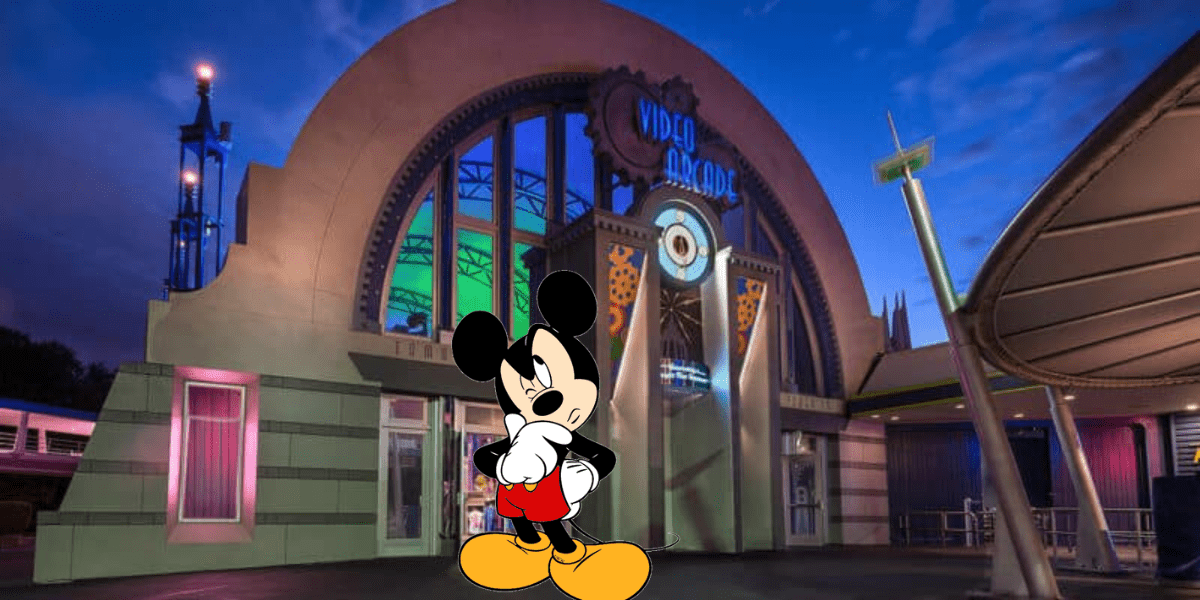 Mickey Mouse pauses thoughtfully at dusk in front of the vibrant, retro-themed Tomorrowland Light & Power Co. arcade at Disney World.