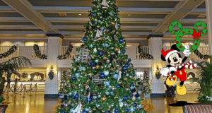 Mickey Mouse in a Santa hat welcomes guests in a dazzling, Disney World–inspired lobby, standing by a grand Christmas tree adorned with festive decorations and holding a sparkling holiday wreath, evoking the heartwarming magic of the season at the park.
