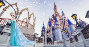 Elsa from Frozen poses in front of Cinderella Castle at Walt Disney World, surrounded by gently falling snowflakes, creating a magical winter scene perfect for guests experiencing the park’s Frozen-themed festivities.