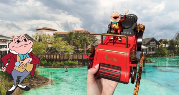 A fan shows off a collectible red Mr. Toad car figure, while Mr. Toad himself grins beside the lagoon at Disney Springs, with shops and waterfront views in the background.