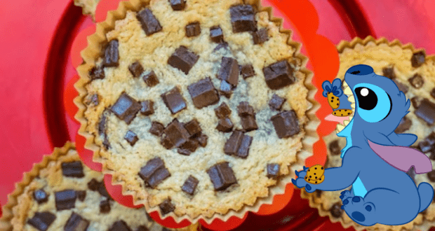 A chocolate chip cookie nestled in a red liner, featuring Stitch in the corner munching on his own cookie—an irresistible Disney treat that captures the whimsy of Walt Disney World and the fun of National Cookie Day.