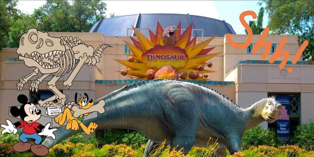 Mickey Mouse and Pluto join dinosaur skeletons for a fun photo op in front of the DINOSAUR attraction at Disney’s Animal Kingdom, with a lively “Shh!” adding to the playful atmosphere.
