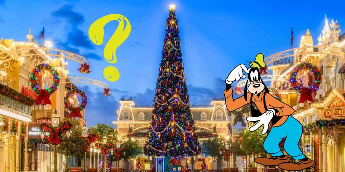 Goofy greets guests with a smile next to a big yellow question mark in a lively town square, as the towering Christmas tree glows in festive lights—reminding everyone at the Disney Parks to check their park reservations and enjoy the holiday magic.