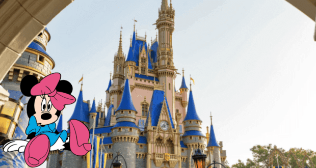 Minnie Mouse, sporting her Walt Disney World Cast Member attire, poses in front of the iconic blue-roofed castle on a bright, sunny day at the park.