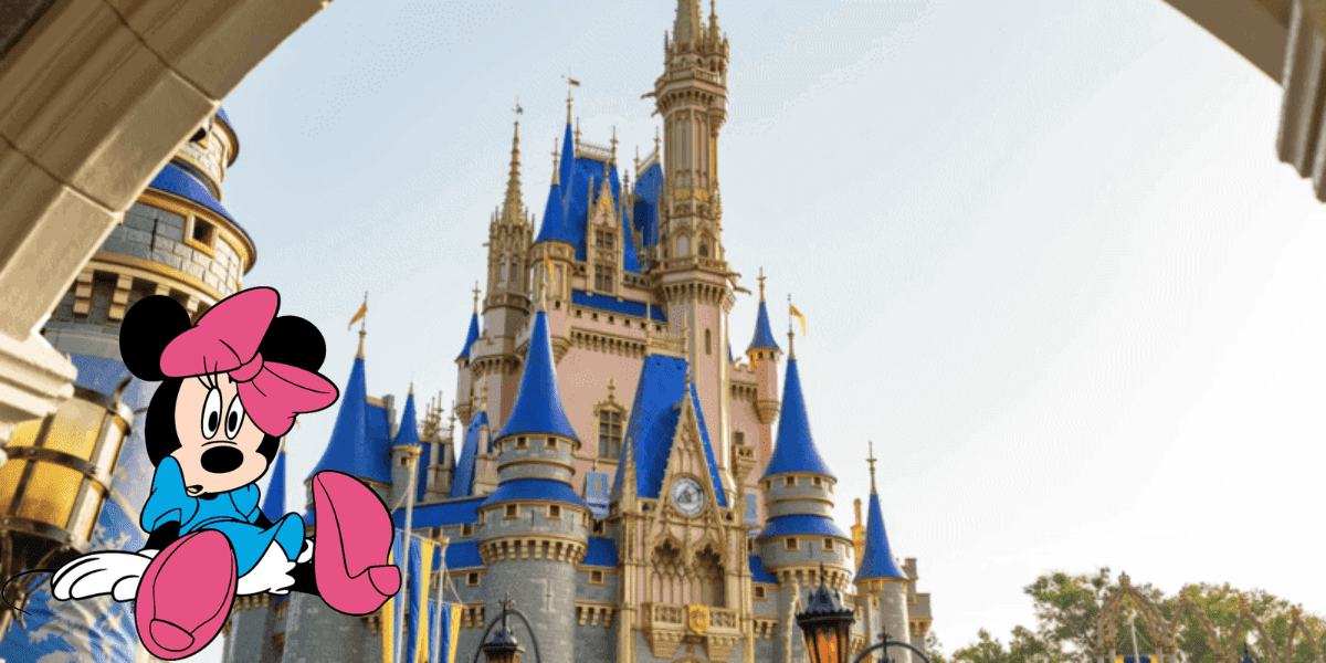 Minnie Mouse, sporting her Walt Disney World Cast Member attire, poses in front of the iconic blue-roofed castle on a bright, sunny day at the park.