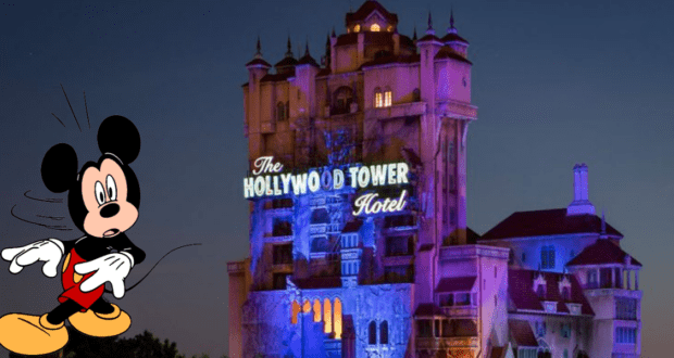 Mickey Mouse greets guests near the glowing Hollywood Tower Hotel attraction at night during a special Disney event.