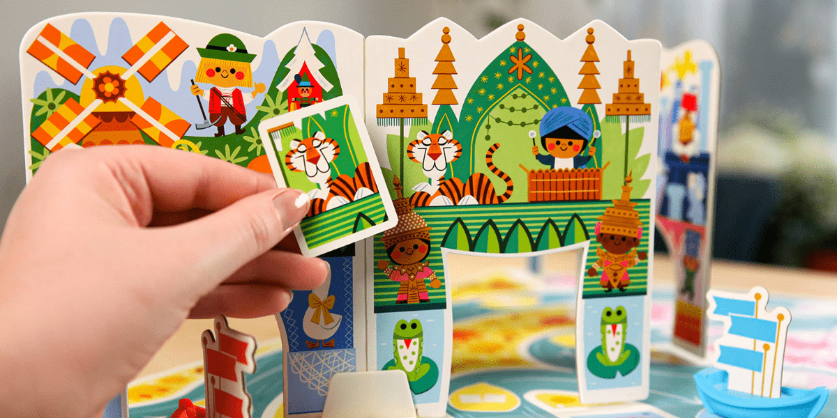A hand displays a card featuring two cartoon tigers beside a vibrant children’s board game filled with playful animal illustrations, capturing the whimsical magic and family fun often experienced at Walt Disney World attractions.
