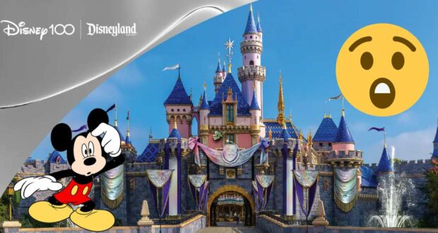 The iconic Disneyland castle dazzles with Disney100 decorations and festive banners, while a giant surprised emoji adds playful flair. Mickey Mouse greets guests enthusiastically in the foreground, capturing the magic of the celebration.