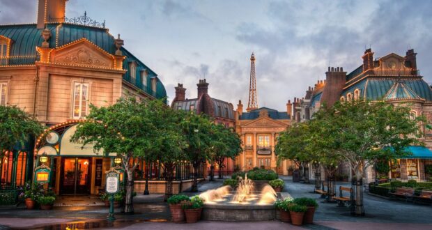 The France Pavilion at EPCOT’s World Showcase features a lively plaza with a sparkling fountain, elegant Parisian architecture, leafy trees, and the iconic Eiffel Tower in the distance—an immersive spot for fans to discover top tips and hidden gems while enjoying this enchanting Disney destination inspired by France.