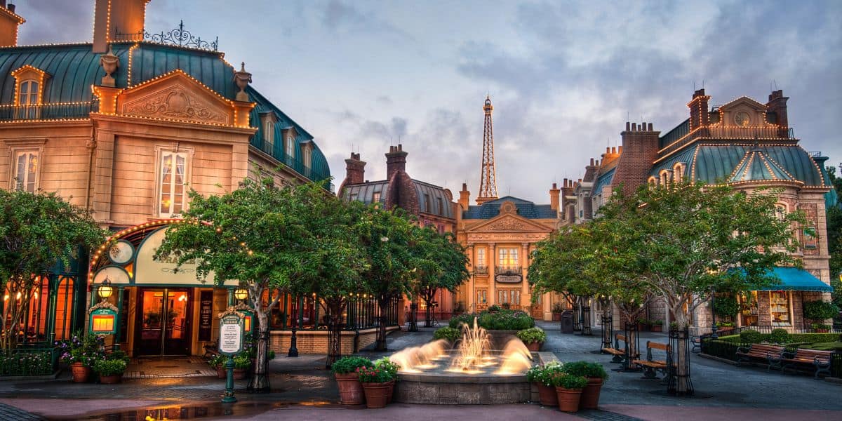 The France Pavilion at EPCOT’s World Showcase features a lively plaza with a sparkling fountain, elegant Parisian architecture, leafy trees, and the iconic Eiffel Tower in the distance—an immersive spot for fans to discover top tips and hidden gems while enjoying this enchanting Disney destination inspired by France.