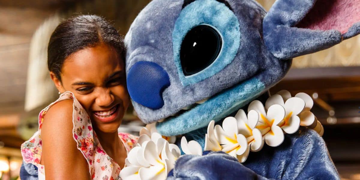 A beaming girl hugs Stitch, decked out in a festive white flower lei, capturing the kind of magical Ohana moment that makes Walt Disney World dining unforgettable.