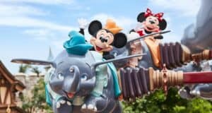 Mickey and Minnie Mouse soar on the flying Dumbo attraction, waving joyfully to fans at a bustling Disney park—an enchanting scene that captures the excitement and magic of planning a dream trip to Tokyo Disneyland with fellow Disney enthusiasts.