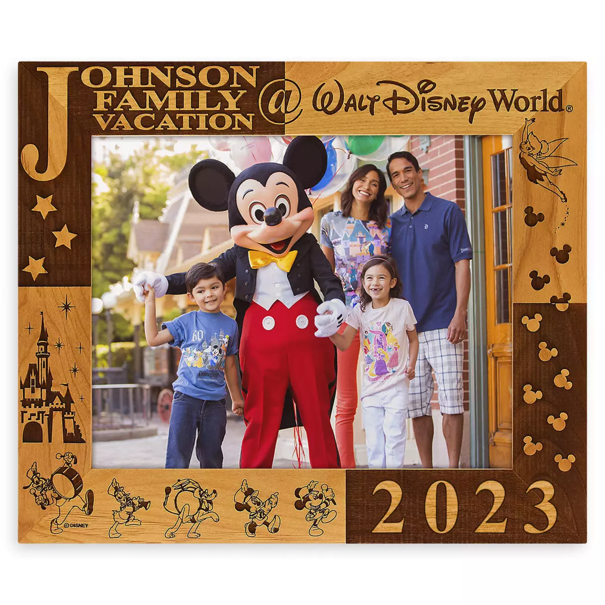 Mickey Mouse joins the Johnson family for a photo at Walt Disney World, all smiles as they display their favorite Disney merchandise inside a wooden "Johnson Family Vacation 2023" frame.