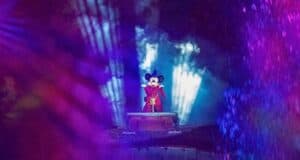 Mickey mouse standing in a red garment with a party hat