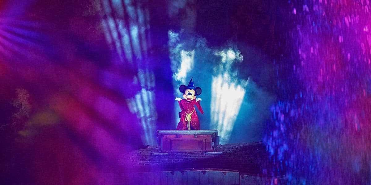 Mickey mouse standing in a red garment with a party hat