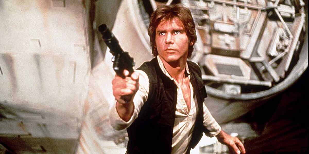 Han Solo in his signature vest takes aim with his blaster inside Star Wars: Galaxy’s Edge, with the Millennium Falcon visible behind him.
