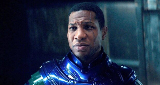 A futuristic blue-armored character with facial scars strikes a serious pose in a dimly lit attraction queue, channeling the same dramatic weight as intense confrontations seen in major pop culture moments.