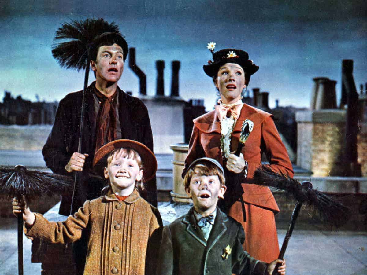 Chimney sweeps in period costumes pose atop a rooftop, grinning and holding their brushes aloft, evoking the joyful spirit of Mary Poppins as seen in classic Disney films.