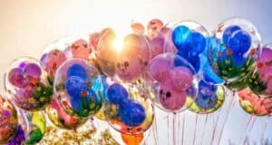 A vibrant cluster of Mickey Mouse balloons shimmers in the sunlight at Disneyland, each one filled with playful flowers and butterflies, perfectly embodying the park’s magical and whimsical atmosphere.
