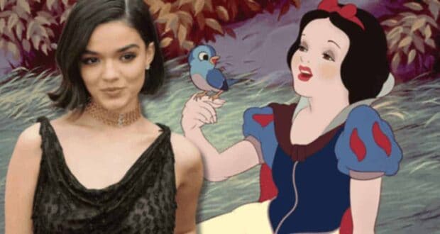 A person in a black dress stands next to an animation of Snow White holding a bluebird. The background features foliage with autumn-colored leaves.