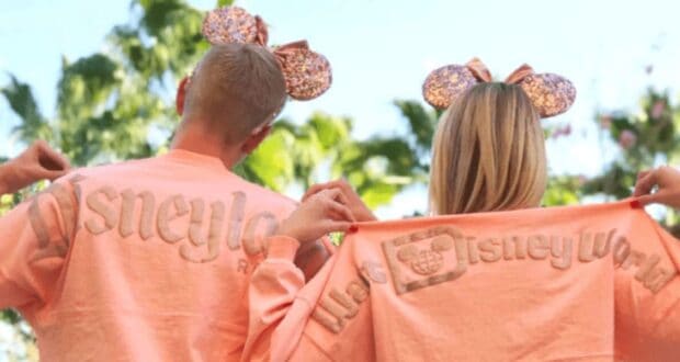 Man and woman wearing peach-colored Disney Spirit Jerseys from the back