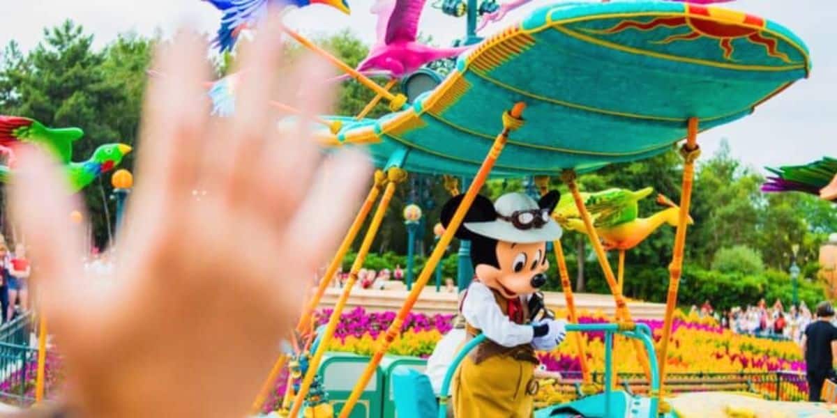 A guest waves at Mickey Mouse on a parade float at Disneyland Paris