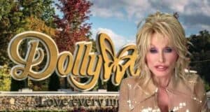 A person with blonde hair and wearing a beige outfit is standing in front of the Dollywood entrance sign. The sign features the word “Dollywood” in gold lettering with a butterfly design and the tagline “Love every moment.” The background includes trees and a cloudy sky.