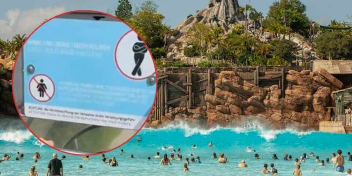 A busy wave pool at a water park with people swimming and playing in the water, one of the top attractions. A rocky mountain and lush greenery are in the background. In the foreground, there is an inset of a sign with safety instructions, though the text on the sign is not fully clear.