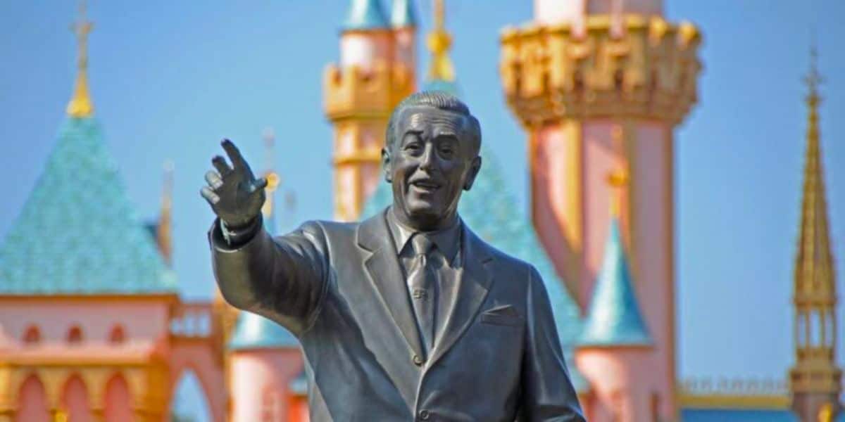 Walt Disney in front of disneyland castle
