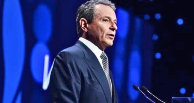 Bob Iger speaking at a podium against a blue-lit backdrop.